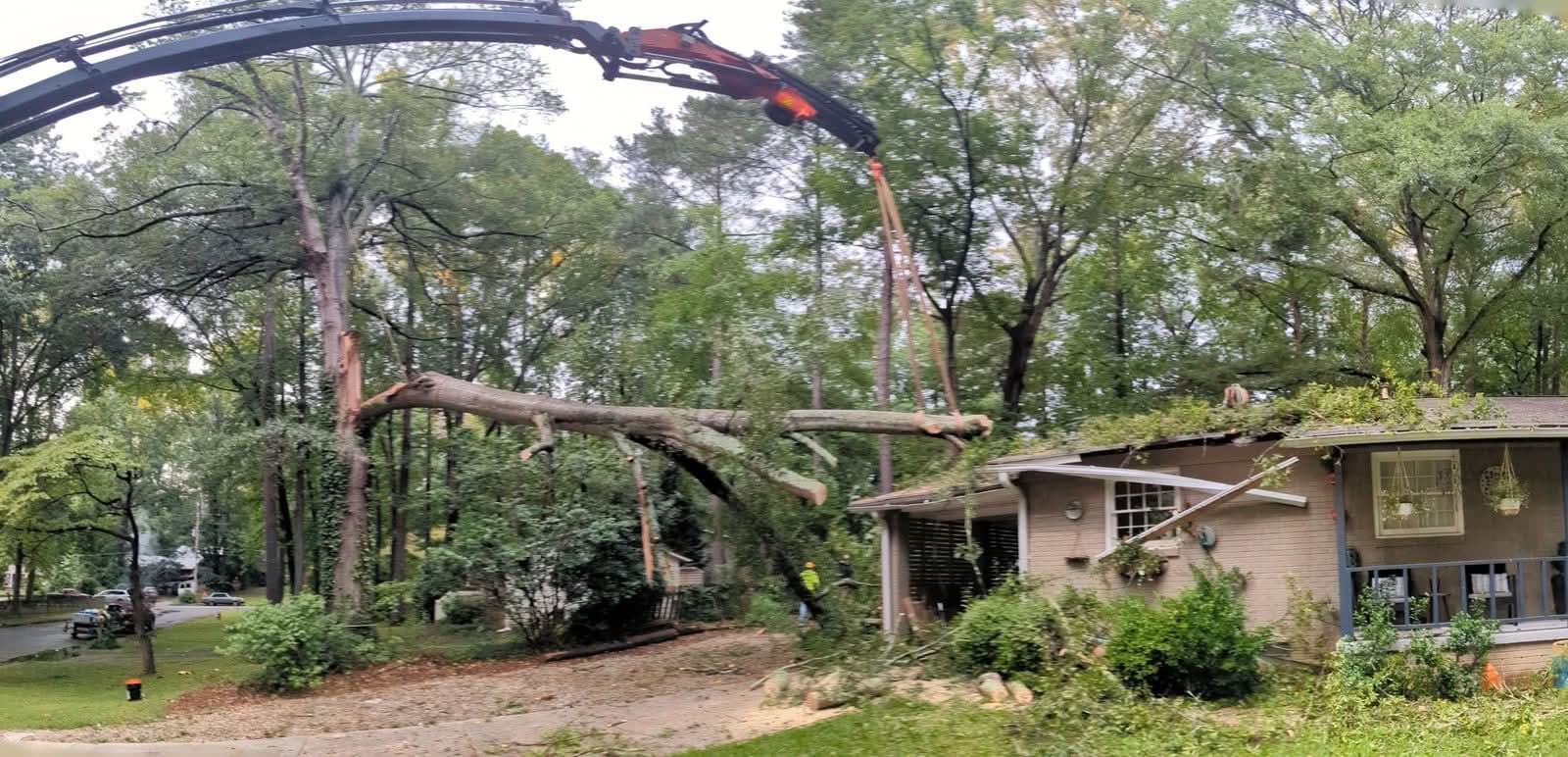 Grapple-saw crane lifting a tree trunk off a house roof in Decatur GA, July 2024