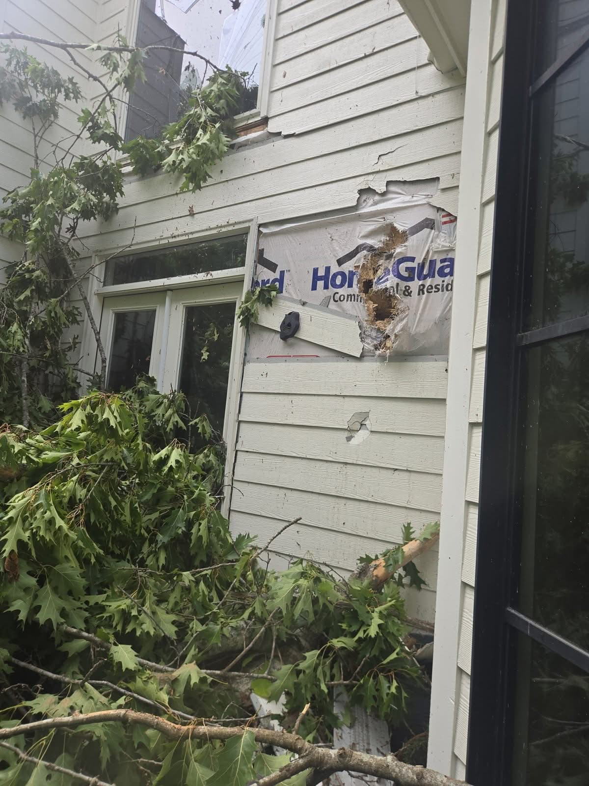 Oak limb punched through the siding of a Woodstock GA home after a tree fell on the house, May 2026