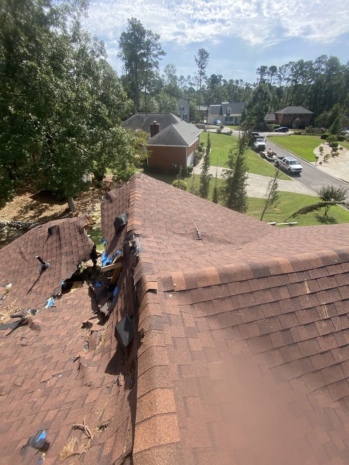 View from a rooftop showing shingle and decking damage after a tree strike