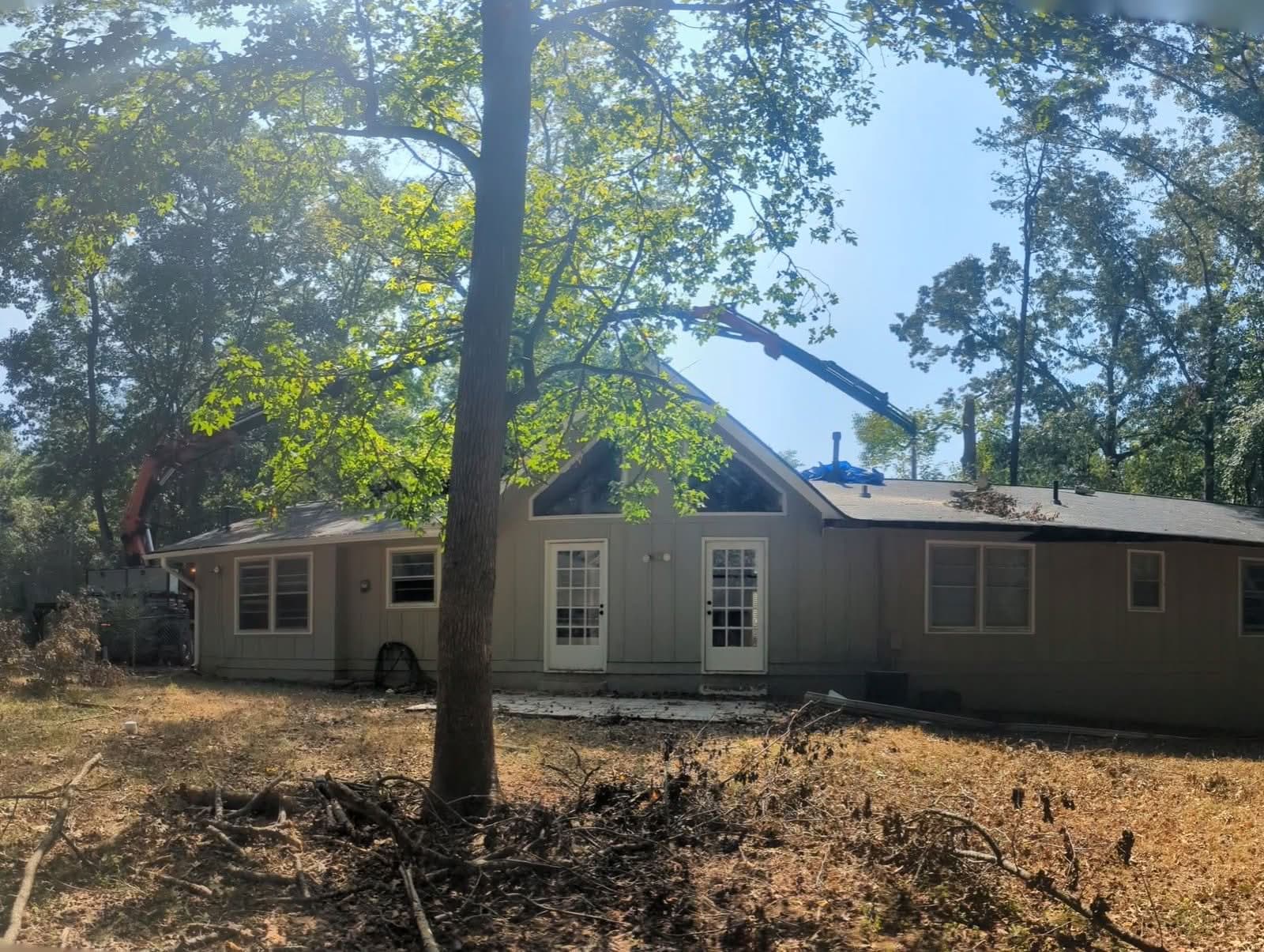 Grapple-saw crane boom reaching over a roofline for tree removal