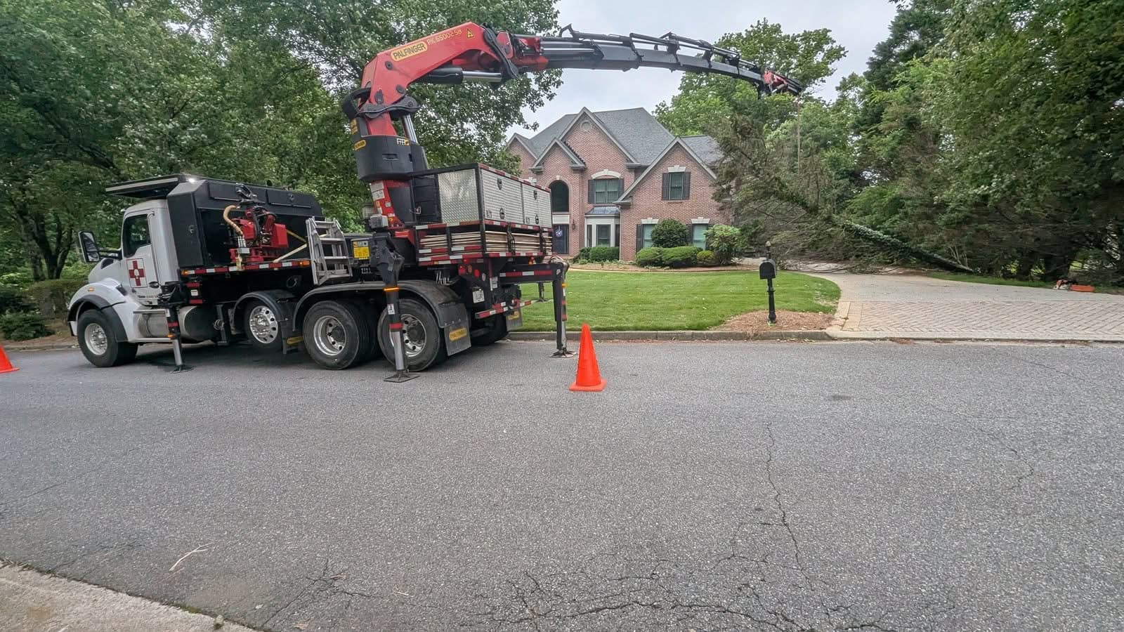 770 Arborist grapple-saw crane truck set up in front of a brick home for tree removal