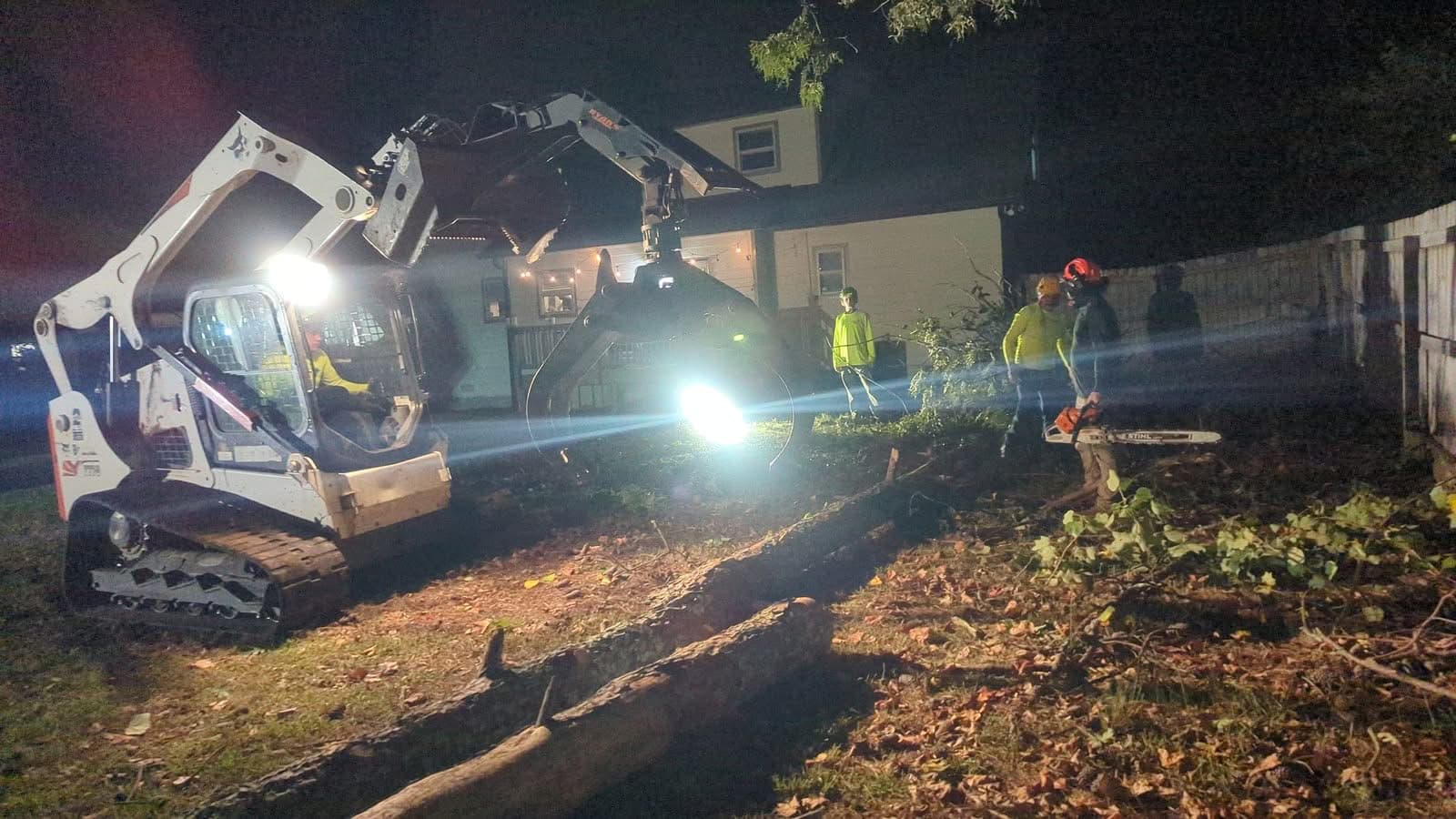 Tree removal crew and skid steer clearing a storm-fallen pine in Kennesaw GA at night, September 2024