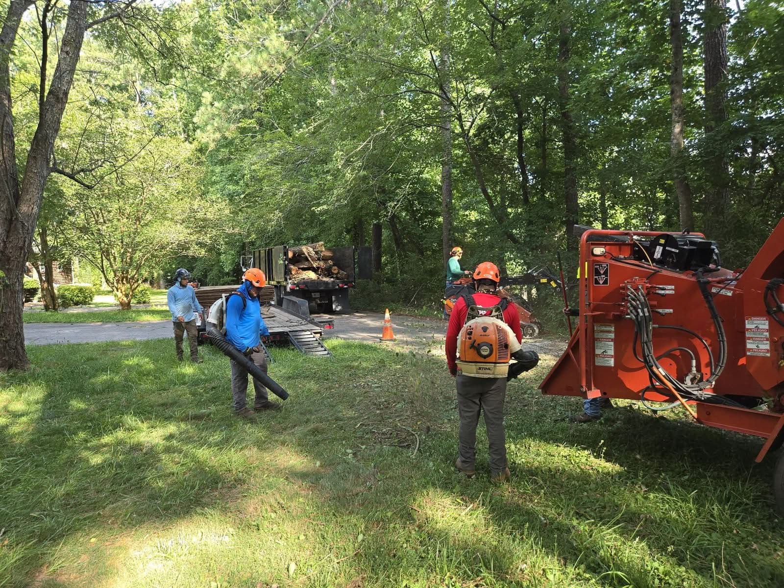 Tree removal crew with backpack blowers, chipper, and loaded log truck cleaning up after a fallen tree in Marietta GA, July 2025