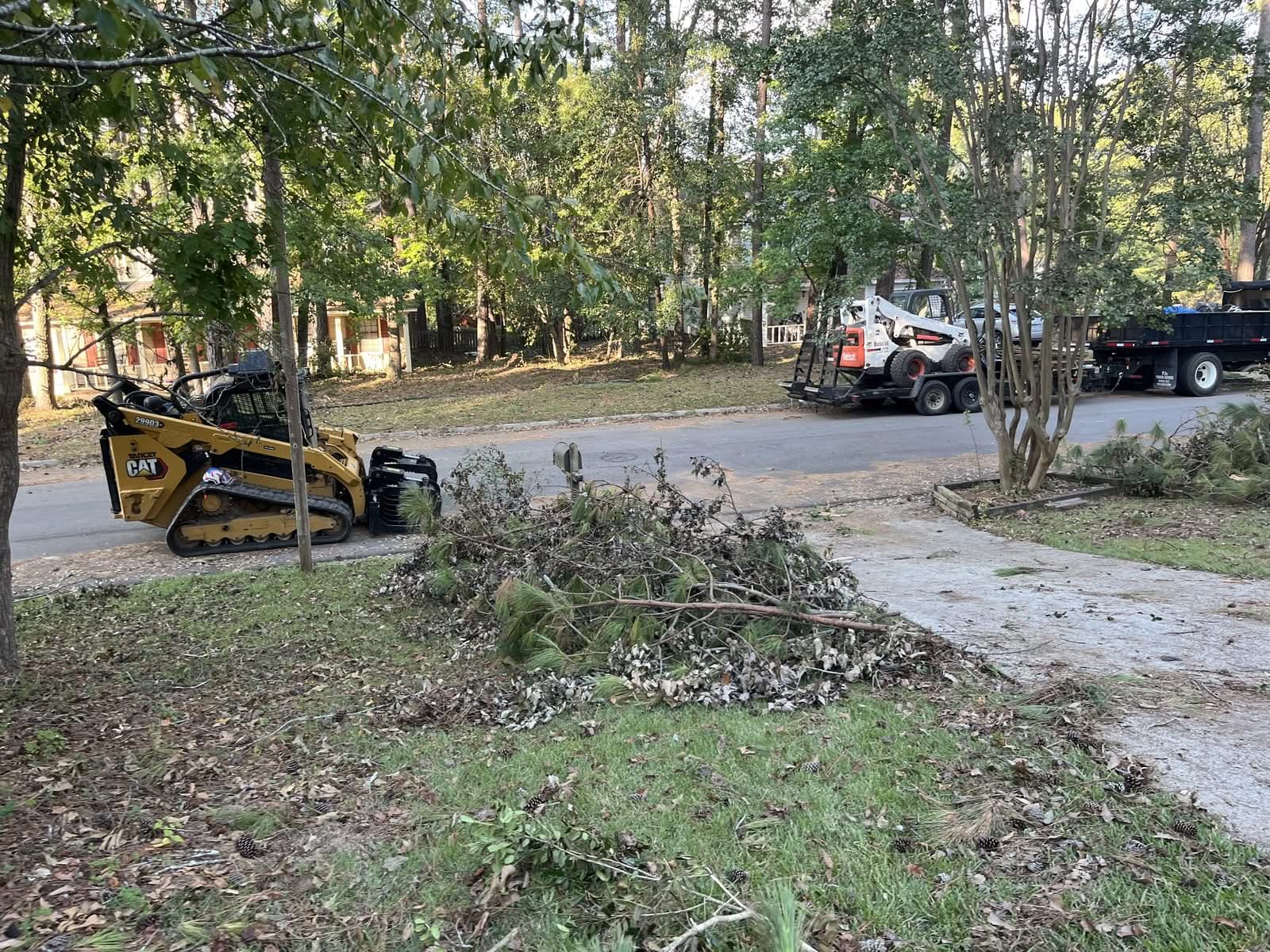 Skid steers and brush piles along a street during storm cleanup