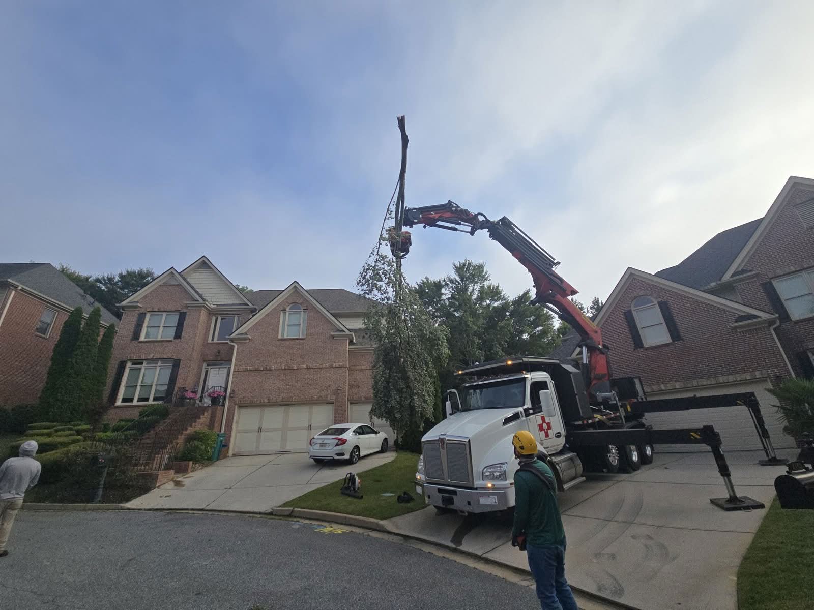 Grapple-saw crane lifting a storm-broken tree section clear of a house in Smyrna GA, June 2025