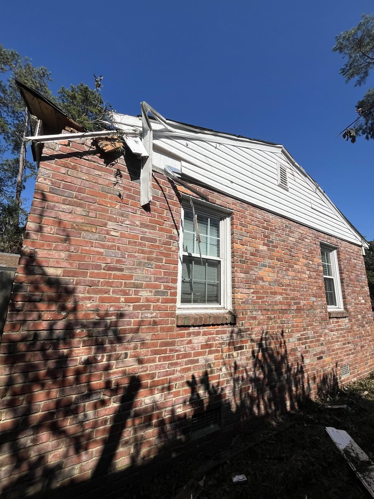 House gable corner sheared open by a falling tree